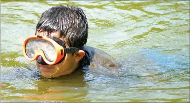  ?? Photo by Randy Moll ?? Joshua Gonzales, 12, of Bentonvill­e surfaces after diving to the bottom of Crystal Lake in Decatur, near the boat ramp, on a hot afternoon, July 20.