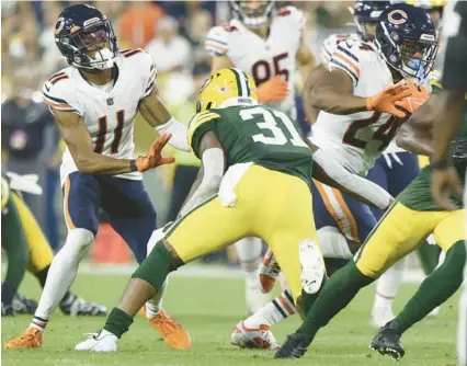  ?? JOHN J. KIM/ CHICAGO TRIBUNE ?? Bears wide receiver Darnell Mooney, left, blocks Packers safety Adrian Amos as running back Khalil Herbert rushes for a first down Sept. 18 at Lambeau Field in Green Bay.