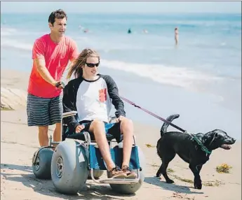  ?? Josh Gill ?? JON MENZIES pushes Sean Goral in a beach wheelchair alongside his dog Spirit in Santa Barbara.