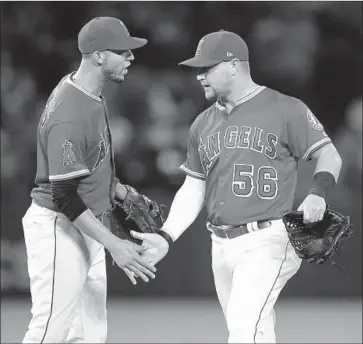  ?? Jae C. Hong Associated Press ?? KOLE CALHOUN, right celebrates the Angels’ victory over the Astros on Monday with Andrelton Simmons. Calhoun hasn’t been hitting much, but he made a big defensive play in the ninth inning of that win.