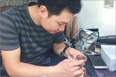  ?? PHOTOS BY LIANG FENGXIN / FOR CHINA DAILY ?? Zhang Neng checks a handicraft item in his swap shop in Guangzhou, Guangdong province.