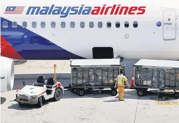  ??  ?? File photo shows a worker loading cargo onto a Malaysia Airlines aircraft. — Reuters photo