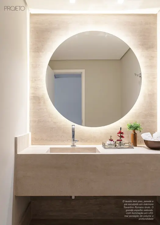  ??  ?? O lavabo tem piso, parede e pia esculpida em mármore Travertino Romano bruto. O grande espelho redondo, com iluminação em LED, traz sensação de volume e profundida­de