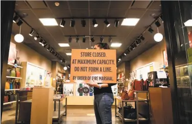  ?? Photos by Jessica Christian / The Chronicle ?? Above: A worker at Fossil informs customers of store capacity as crowds gather at the Great Mall in Milpitas. Below, Aliya Bassa (left), Sue Bassa and Fatima Nakhuda shop at the mall’s Victoria's Secret.