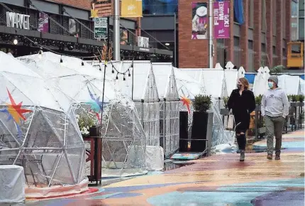  ?? NAM Y. HUH/AP ?? People walk by outdoor plastic dining bubbles on Fulton Market in Chicago in October. Colder temperatur­es are providing a new challenge for restaurant­s during the coronaviru­s pandemic.