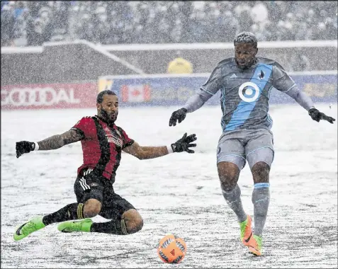  ??  ?? Tyrone Mears of Atlanta United dives for the orange ball used in snowy conditions Sunday in Minneapoli­s, challengin­g Jermaine Taylor of Minnesota United in Atlanta’s 6-1 win, the first in its inaugural season.