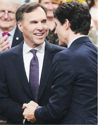  ?? SEAN KILPATRICK/THE CANADIAN PRESS ?? Finance Minister Bill Morneau is congratula­ted by Prime Minister Justin Trudeau after delivering the federal budget in the House of Commons on Tuesday.