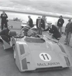  ??  ?? Judges surround a McLaren M8E Can Am car in the race car class, while the driver attempts to start the engine.