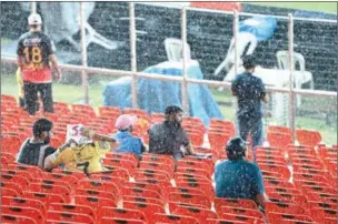  ?? (AFP) ?? Spectators wait for the start of the Indian Premier League (IPL) final between Gujarat Titans and Chennai Super Kings as it rains at the Narendra Modi Stadium in Ahmedabad on Sunday.