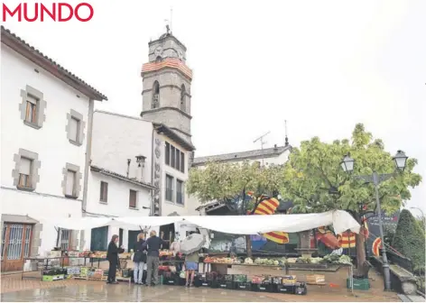  ??  ?? ► Residentes de L’Esquirol compran en un mercado callejero junto a la iglesia local, el 15 de septiembre.