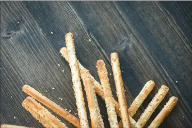  ?? TRIBUNE CONTENT AGENCY ?? Aside from Parmesan, roll the breadstick­s in sesame seeds for a different flavor.