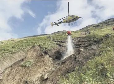  ??  ?? 0 A helicopter uses water in a bid to manoeuvre boulders into safe location down channel