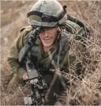  ?? (IDF) ?? A MEMBER of the elite Duvdevan unit crawls through the brush. Soldiers from this unit, along with from elite units Egoz, Maglan and Rimon, will soon prepare for combat together at a new commando training school.