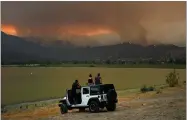  ?? AP PHOTO BY JAE C. HONG ?? Onlookers watch as a wildfire burns near Lake Elsinore, Calif., Wednesday, Aug. 8.