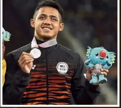  ?? — AFP / Reuters ?? Medals well earned: Rhythmic gymnast Amy Kwan Dict Weng acknowledg­ing the cheers after her bronze-medal finish in the individual all-around. Inset: Para athlete Muhd Afiq Mohamad Ali Hanafiah posing with his bronze medal in the men’s 100m T12.