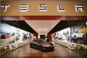  ?? Getty Images ?? People look at a Tesla Motors vehicle on the showroom floor at the Dadeland Mall in 2014 in Miami. Lawmakers in Connecticu­t want to allow the electric vehicle manufactur­er to have the ability to sell its cars directly to consumers in the state.