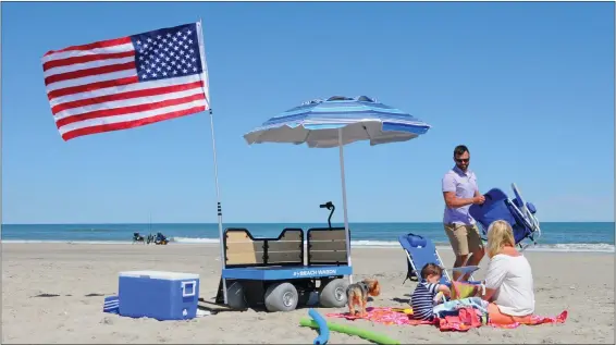  ?? SUBMITTED PHOTO ?? The Mogan family spreads out their gear on the beach in Cape May after an easy walk there with the e-Beach cart doing the grunge work of transporti­ng their items. Now emptied out, the eBeach Wagon makes a comfortabl­e little chair or table up off the sand if needed for their toddlers or other use.