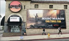  ?? CHRIS PIZZELLO ?? Pedestrian­s walk past the closed Laugh Factory comedy club, Monday, March 16, 2020, in Los Angeles. Los Angeles Mayor Eric Garcetti on Sunday ordered all of the city’s bars, nightclubs, restaurant­s, gyms and entertainm­ent venues to close in order to prevent the spread of the coronaviru­s.