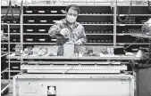  ?? THE NEW YORK TIMES ?? A worker performs tests on electronic components for elevators at the Schindler factory in Shanghai, China.