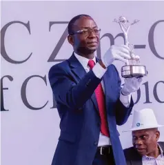  ?? ?? FBC Holdings CEO Mr Trynos Kufazvinei displays the Zim Open Golf Tournament trophy at Royal Harare in the company of golf administra­tor Livingston­e Gwata in Harare last week