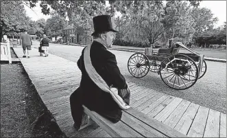  ??  ?? Mike Follin, playing the mayor of Ohio Village, told visitors about the replica of a 1898 runabout, parked in the street. In 1895, manufactur­er John Lambert built a three-wheeled runabout that often tipped over. By 1898, Lambert had added a fourth wheel.