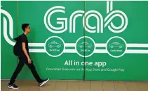  ?? REUTERS ?? A MAN WALKS PAST a Grab office in Singapore, March 26.