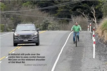  ?? MURRAY WILSON/STUFF ?? A motorist still pulls over the centre line to pass cyclist Duncan Mccann on the widened shoulder of Old West Rd.