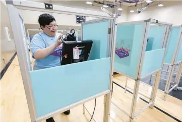  ?? ETHAN MILLER/GETTY ?? A Clark County, Nevada, election worker sets up a voting machine Thursday at a polling place in Las Vegas.