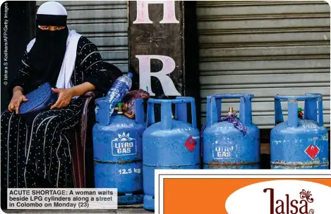  ?? ?? ACUTE SHORTAGE: A woma wait beside LPG cylinders along a treet in Colombo on Monday 23