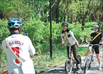  ?? WANG FEI / FOR CHINA DAILY ?? Cyclists pose for photos to capture a moment on a greenway at Wanghe Park in Beijing’s Chaoyang district on April 16.