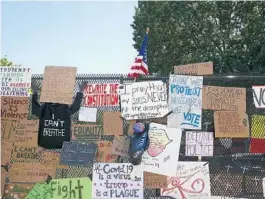  ?? TASOS KATOPODIS/GETTY ?? Signs calling to “defund the police” join others on a steel fence at Lafayette Park near the White House.