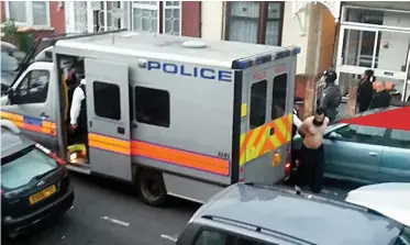  ??  ?? Held: A shirtless man is led from the house in East Ham targeted by police yesterday
