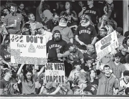  ?? Brett Coomer / Staff photograph­er ?? Fans hold signs directed at umpire Joe West, whose call of fan interferen­ce on a possible Astros home run in Game 4 stirred controvers­y, during Game 5 of the American League Championsh­ip Series on Thursday at Minute Maid Park.