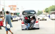  ??  ?? Two men perch in the boot of a Honda Fit along Fort Street in Bulawayo recently. The drivers of the vehicles commonly used as pirate taxis continue playing cat and mouse with law enforcemen­t agents in the city