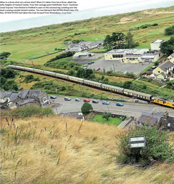  ?? Greg Mape ?? When is a drone shot not a drone shot? When it's taken from terra firma, albeit the lofty heights of Harlech Castle. From this vantage point Pathfinder Tours' ‘Cambrian Coast Express' from Bristol to Pwllheli is seen on the outward leg crawling over the level crossing outside Harlech station. The two Network Rail ERTMS-fitted Class 37s Nos. 97304+97303 had taken the train forward from Shrewsbury.