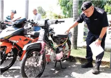  ?? — Bernama photo ?? Abang Zainal Abidin takes a closer look at one of the confiscate­d motorcycle­s.