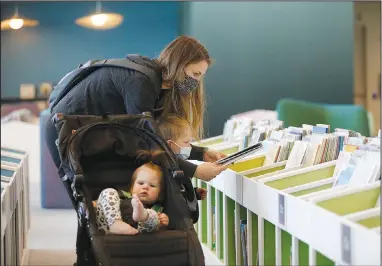  ?? (NWA Democrat-Gazette/David Gottschalk) ?? Rachel Sabatini selects books Monday with her son Cooper, 3, and daughter Maisyn, 1, in the preschool area of the Fayettevil­le Public Library’s new expanded area. The library opened last month with some sections unavailabl­e to the public because of the covid-19 pandemic. Go to nwaonline.com/210223Dail­y/ and nwadg.com/photos for a photo gallery.