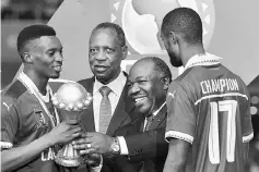  ??  ?? Cameroon’s forward Benjamin Moukandjo (left) and Cameroon’s defender Nicolas Nkoulou (right) are handed the winner’s trophy by Gabonese President Ali Bongo Ondimba as President of the Confederat­ion of African Football (CAF) Issa Hayatou (second left)...