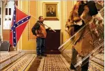  ?? ERIN SCHAFF / THE NEW YORK TIMES ?? Amember of the mob of Trump supporters carries the Confederat­e flflag inside the Capitol building as Congress’ sessionwas forcibly disrupted Wednesday.