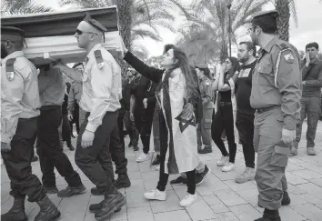  ?? ODED BALILTY AP ?? The wife of Israeli reservist Yair Cohen touches his flag-draped casket during his funeral at Kiryat Shaul military cemetery in Tel Aviv on Tuesday. Cohen, 30, was killed during Israel’s ground campaign in the Gaza Strip.