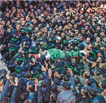  ?? AFP ?? The body of Hamas official Mazen Faqha is carried by members of the Ezz Al Deen Al Qassam Brigades, the military wing of Hamas, during his funeral in Gaza City yesterday.