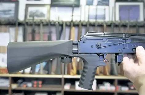  ?? GEORGE FREY/GETTY IMAGES ?? A bump stock device (left) that fits on a semi-automatic rifle to increase the firing speed, making it similar to a fully automatic rifle, is installed on a AK-47 semi-automatic rifle, (right) at a gun store in Salt Lake City, Utah. The U.S. Congress...