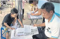  ??  ?? Mr Jakkrit and his family sort out the lottery pullout pages which are sold along with Prachamati newspaper at the beginning and middle of every month.