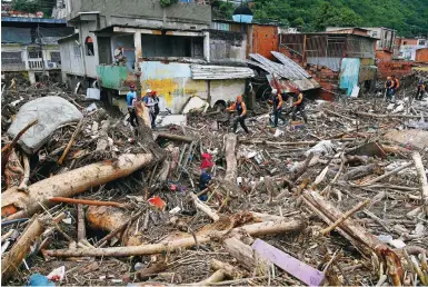  ?? Photo: AFP ?? Rescuers and family members search through the rubble of houses swept away by floodwater­s in Las Tejerias, Aragua state.