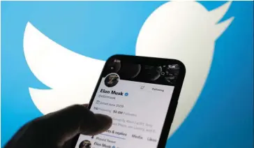  ?? — AFP ?? Hiring freeze: An illustrati­on photo displaying Musk’s account with a Twitter logo in the background. The company has suspended hiring, and even showed a few senior executives the exit.