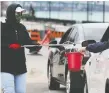  ?? JANISSE DAN ?? CUPE member Cassandra Gawne uses a multi-use grabber and bucket to collect money during the annual Goodfellow­s newspaper drive that adopted new safety protocols this year because of COVID-19.