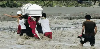  ?? BULLET MARQUEZ/ THE ASSOCIATED PRESS ?? Relatives cross a river to bury their loved one, who died in flooding caused by typhoon Bopha in the Philippine­s.