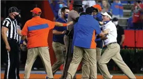  ?? (AP/The Gainesvill­e Sun/Brad McClenny) ?? Florida Coach Dan Mullen (right) is held back by coaches and law enforcemen­t after a fight broke out at the end of the first half of the Gators’ game Saturday against Missouri in Gainesvill­e, Fla. The SEC docked Mullen $25,000 on Monday for his role in the brawl, in addition to issuing suspension­s for players who were involved.