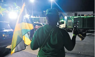  ?? GLADSTONE TAYLOR/MULTIMEDIA PHOTO EDITOR ?? A solitary Jamaica Labour Party supporter rings her bell and chants in the Jamaica Labour Party headquarte­rs parking lot, minutes before 9 p.m. on Monday.