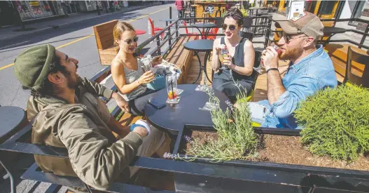  ?? JOHN MAHONEY ?? Roommates, from left, Clément Buyse, Elena Hasse, Caroline Dujardin and Oswald De Cruz enjoy drinks on the terrace of Les Enfants du Rock in Montreal’s Plateau Mont-royal district on Thursday. The provincial government announced that bars can reopen for the first time since the pandemic lockdowns.